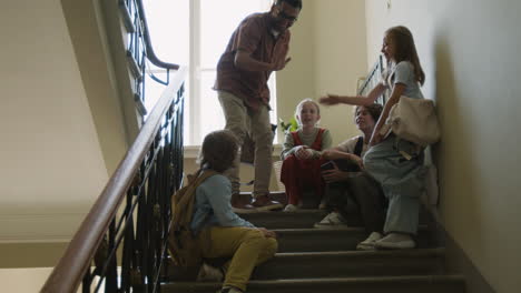 teacher and students talking and high-fiving on school stairs
