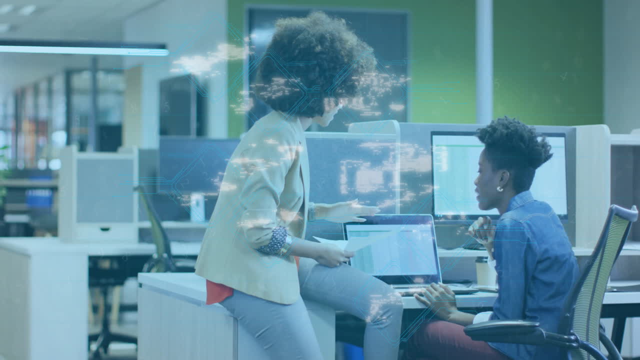 Collaborating in office, two women with digital security animation overlaying scene