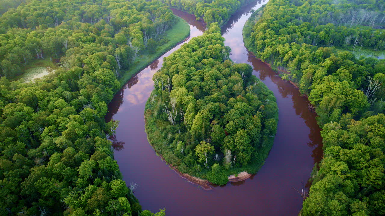 Drone shot flying over big bend of wild Manistee river on a foggy, misty morning in summer