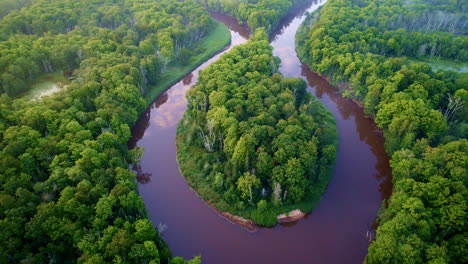 drone shot flying over big bend of wild manistee river on a foggy, misty morning in summer