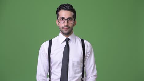 joven empresario persa barbudo y guapo contra un fondo verde