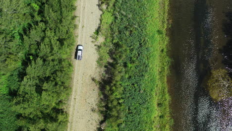 Aerial-Top-Down-Drone-View-Of-Four-Wheel-Drive-Off-Road-Driving-On-Gravel-By-Creek-In-Australia-4K