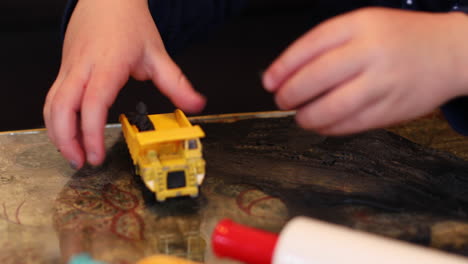 a close-up of a child's hands playing with his tow digger and clay inside during lockdown