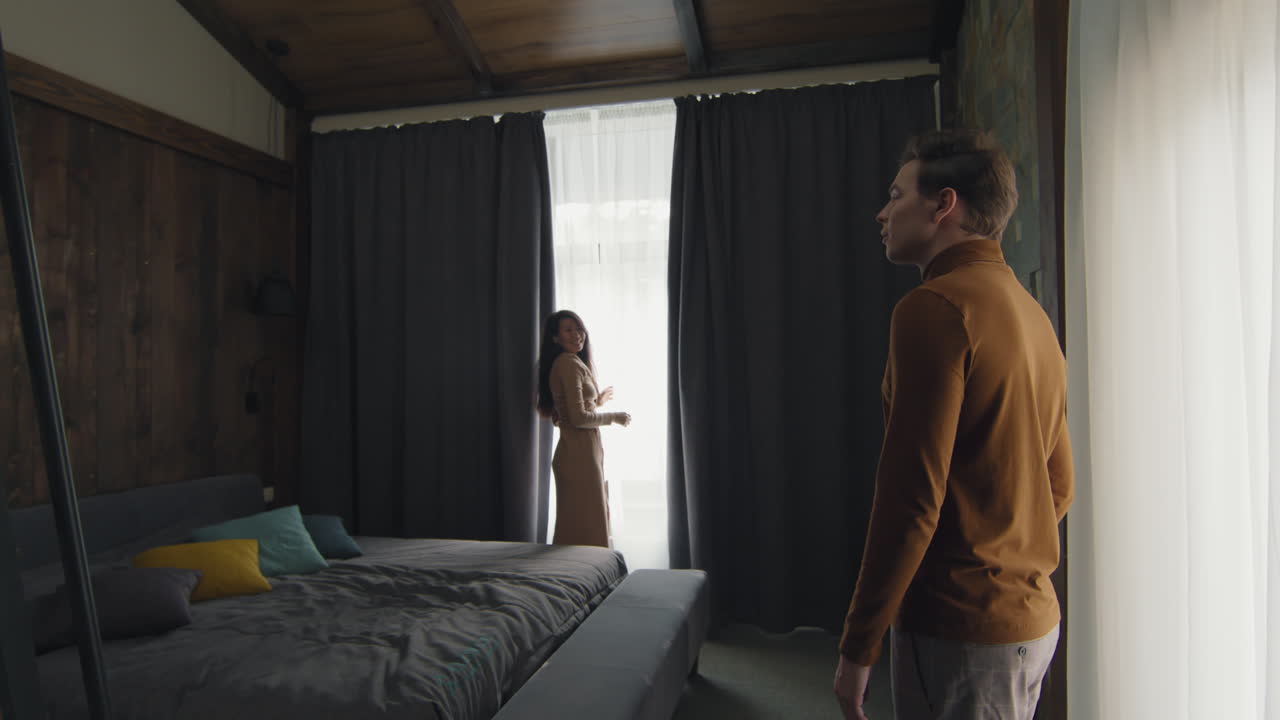 Couple Looking Out a Window in a Cozy Bedroom