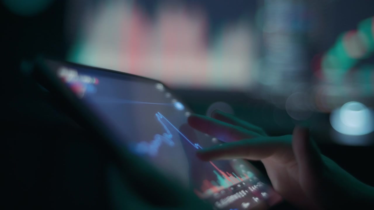 Person's hands scrolling through stock market charts on a tablet