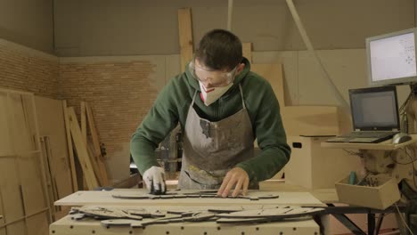 a worker paints a wooden product with a sponge. painting of plywood products made on a cnc laser machine.