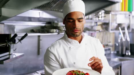 chef masculino sosteniendo un plato de comida en una cocina comercial
