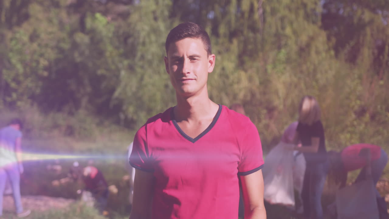 video de luces sobre un hombre caucásico feliz recogiendo basura con voluntarios en el campo