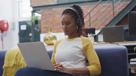 mujer de negocios afroamericana feliz usando una computadora portátil en la oficina