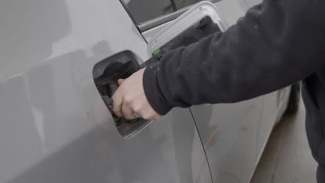 gas station white caucasian man with wedding ring filling up silver car pressing and opening fuel tank cover and twisting removing gas cap and turning towards pump