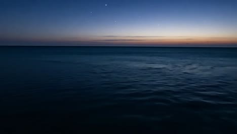 calm ocean and colorful sky at sunrise emerge slowly from a black background, creating a serene and tranquil scene