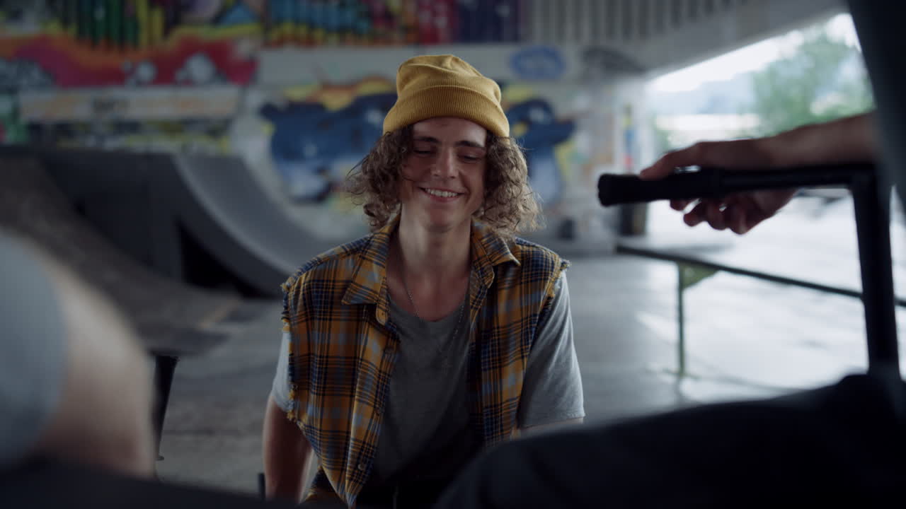 amigos sonrientes disfrutando de la conversación juntos en la pared de graffiti del parque de skate.