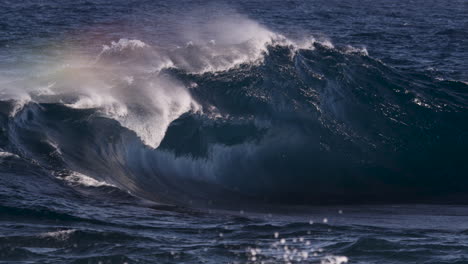 angry looking ocean before a swell line turns into a heaving wave as it breaks onto a rock shelf close to the rocky shore