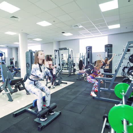 strong woman bodybuilders doing workout in a modern gym. muscular girls in sportswear exercising heavily. camera moves back.