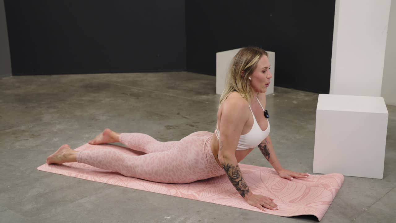 Focused woman lying on a pink mat for ab exercises during a core training session stretching in cobra position and rising into childs pose