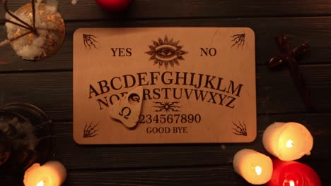 ouija board seance with lit candles on a dark wooden table