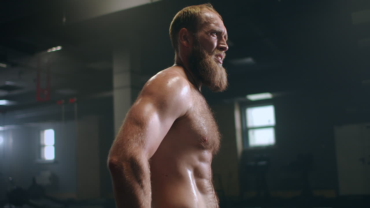 hombre barbudo cansado con vapor en el cuerpo en el gimnasio se recupera después del entrenamiento