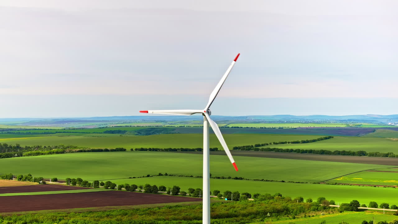 Aerial drone view of a wind turbine in a field on a cloudy day
