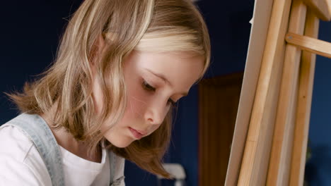 close up view of a girl's face concentrating and painting on a lectern in living room