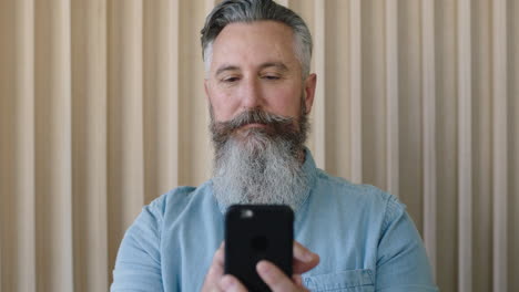 close up portrait of mature caucasian man stylish beard texting browsing using smartphone mobile technology looking pensive focused