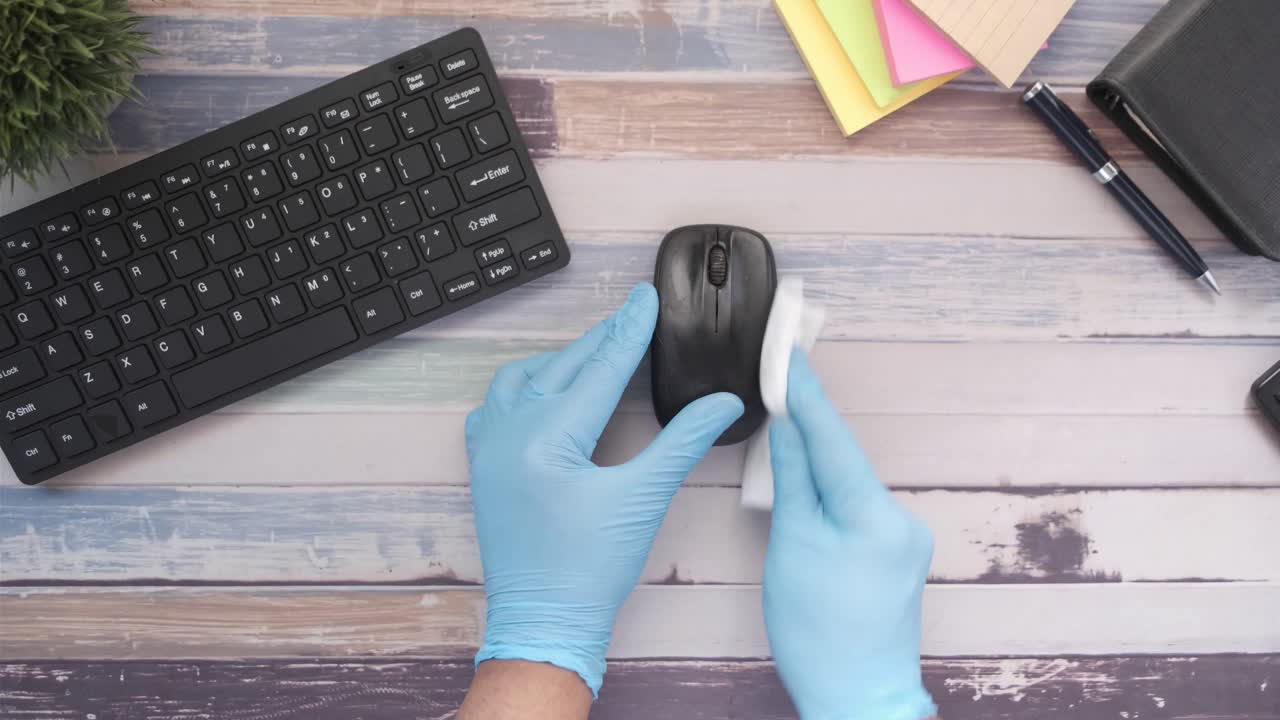 limpieza de un ratón y un teclado de computadora con guantes