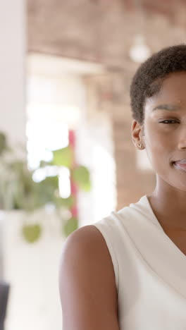vertical video of portrait of happy african american casual businesswoman in office in slow motion