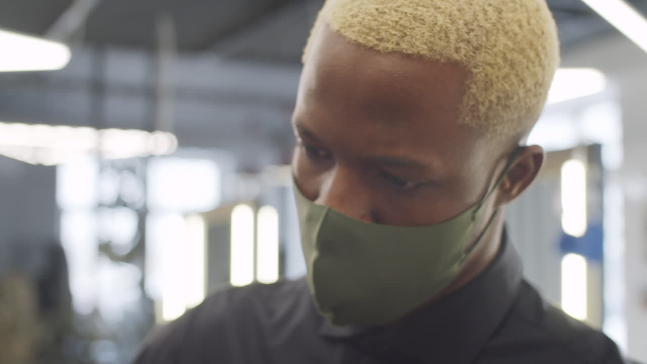 마스크 를 입은 남성 이발사 가 고객 의 머리카락 을 자르고 있다