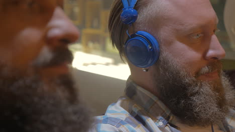 Close-up-view-of-two-bearded-men-listening-musics-using-colorful-on-ear-headset