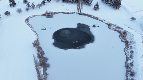 Aerial-view-of-a-frozen-pond-on-a-well-maintained-golf-course