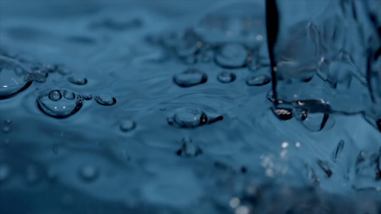 Nahaufnahme von Wasser, das auf eine blaue Oberfläche gießt und spritzt.