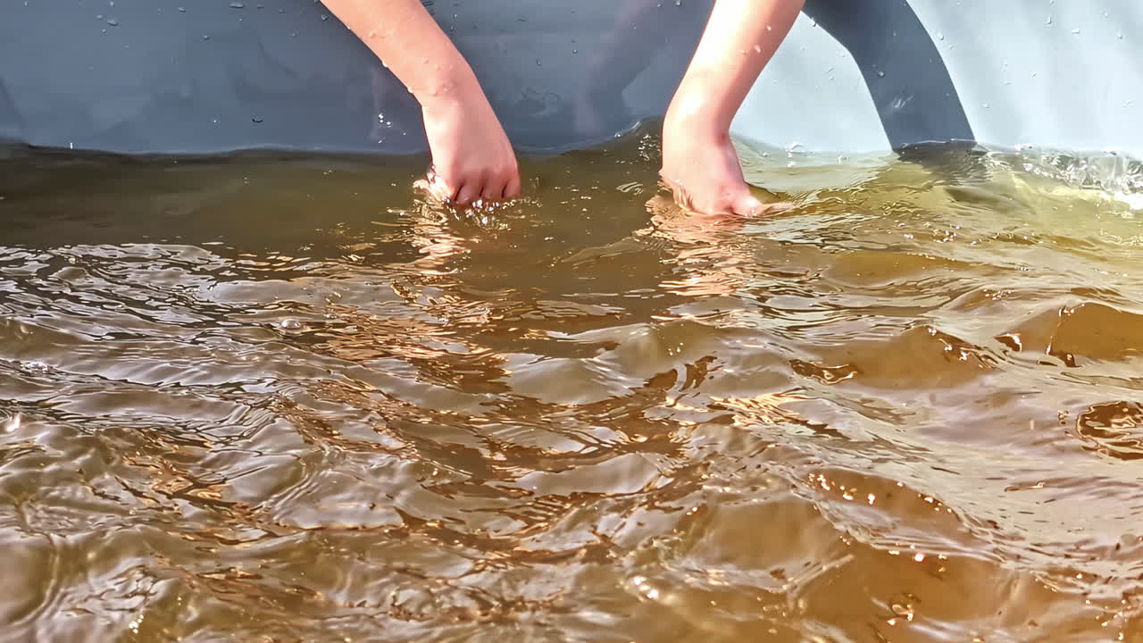 Bare hands splashing in brownish pool water during sunny day outdoors