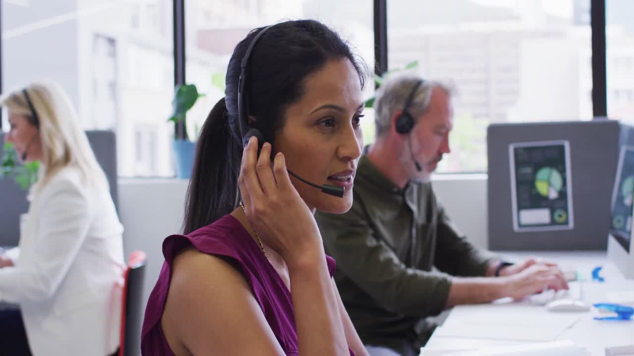 retrato de una mujer de negocios de raza mixta sentada usando una computadora hablando en auriculares de teléfono en la oficina