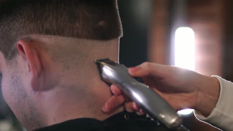 Vista-De-Cerca-Del-Peinado-Masculino-En-Una-Barbería-Con-Recortador-Profesional.-Corte-De-Pelo-Del-Hombre-En-Peluquería-Con-Cortapelos-Eléctrico.-Arreglar-El-Cabello.