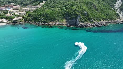 Un-Barco-Navegando-A-Toda-Velocidad-En-Las-Cristalinas-Aguas-Azules-Cerca-De-La-Isla-De-Corfú,-Grecia,-Vista-Aérea