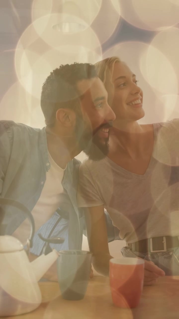 Video vertical: Pareja en una mesa, mujer levantando el teléfono para tomarse una selfie para redes sociales, con superposición de efecto bokeh