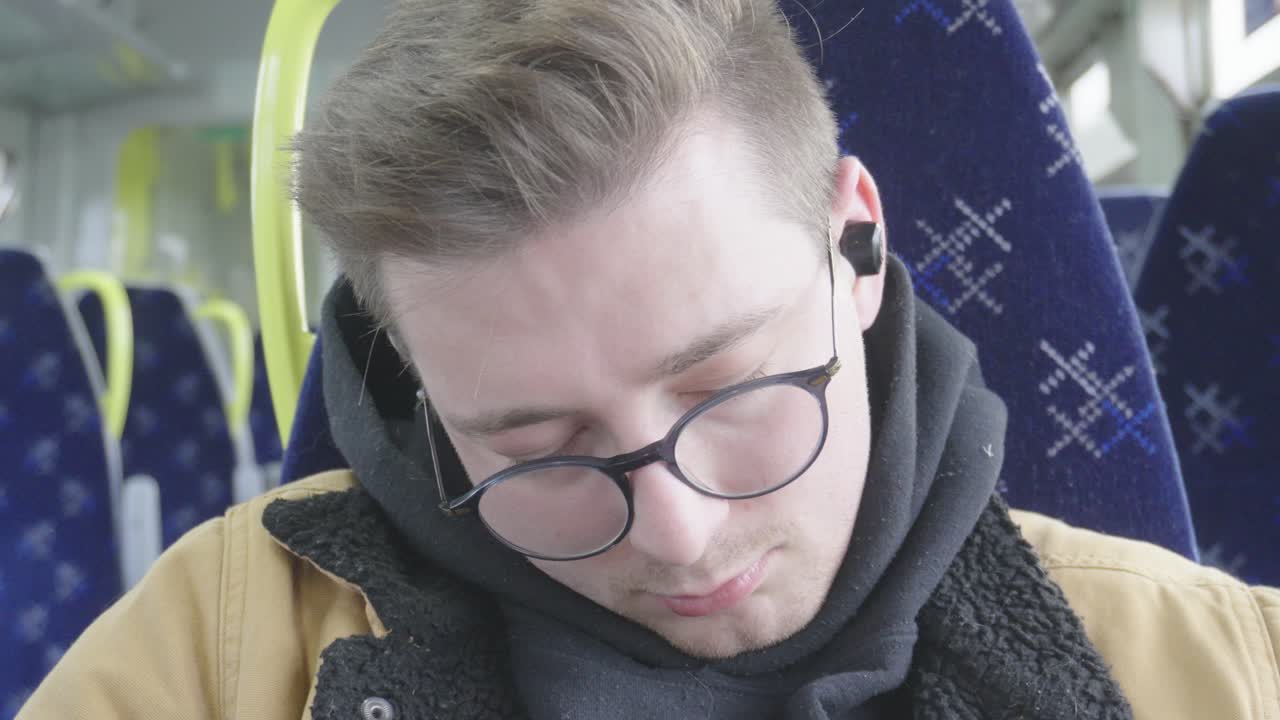 Close-up of young man wearing glasses sleeping in train wagon