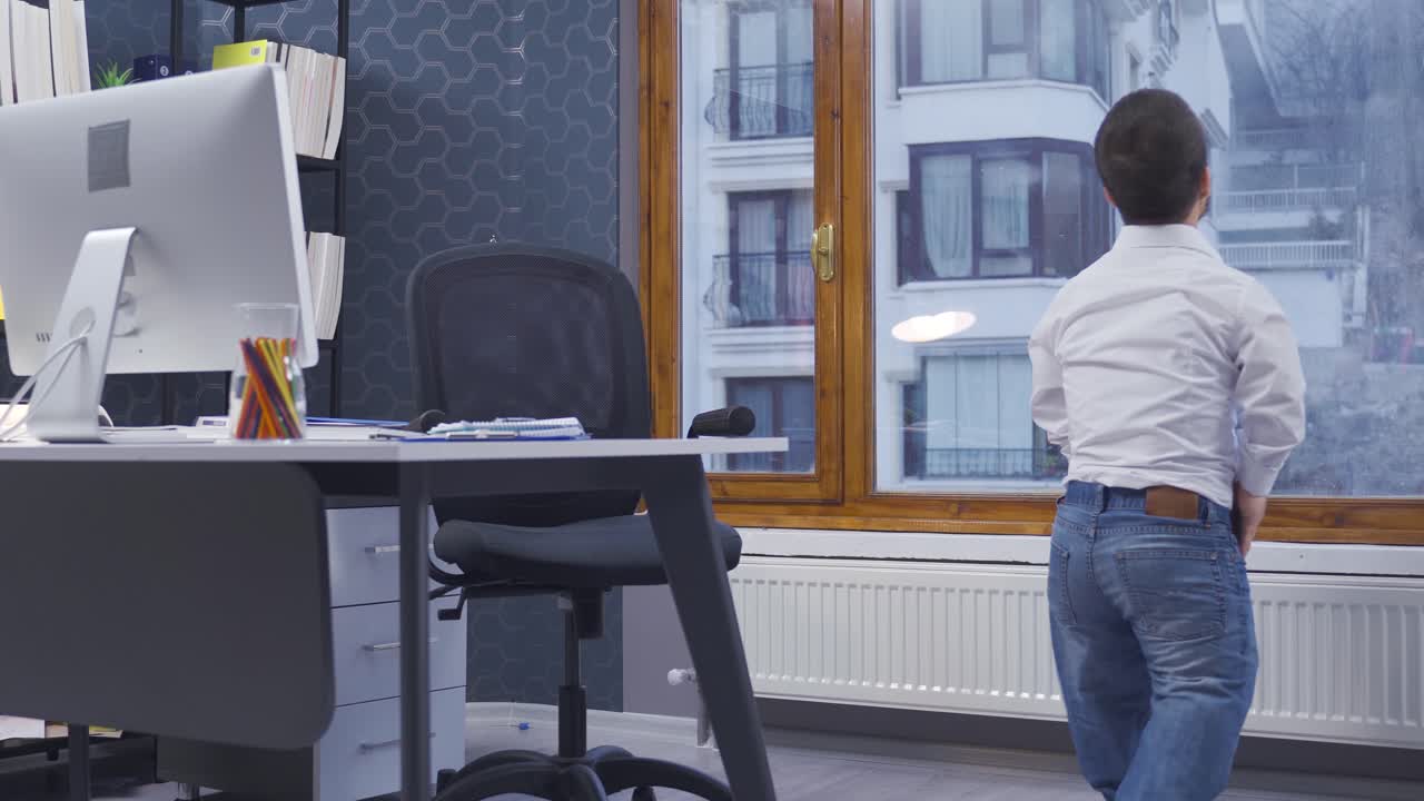 사무실에서 일하는 행복한 난쟁이 남자. 그는 일어나서 밖을 바라본다.