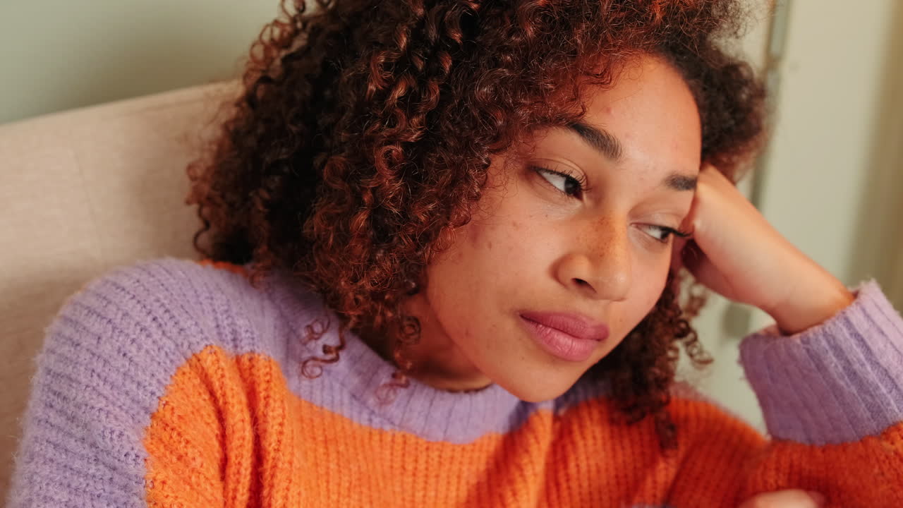 Pensive Young Woman with Curly Hair Resting Indoors