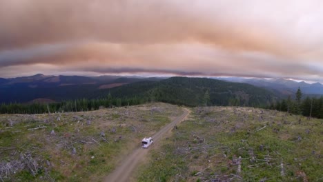 Camper-Van-Fährt-Alleine-Einen-Schotterweg-In-Den-Bergen-Mit-Rauchigem-Himmel-Hinunter,-Hohe-Bildrate-Aus-Der-Luft-59