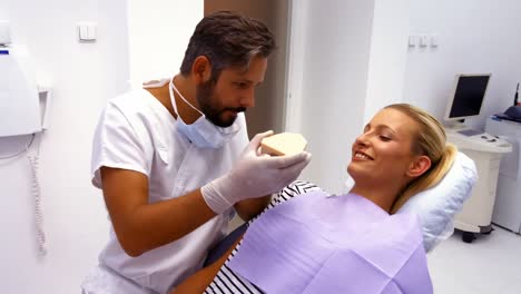 Dentist-showing-model-teeth-to-female-patient