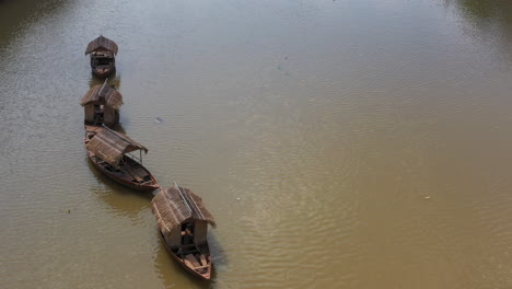 aerial view of a line of four small traditional asian fishing boats are tied up in a canal and moving with flow of water and wind part two of two