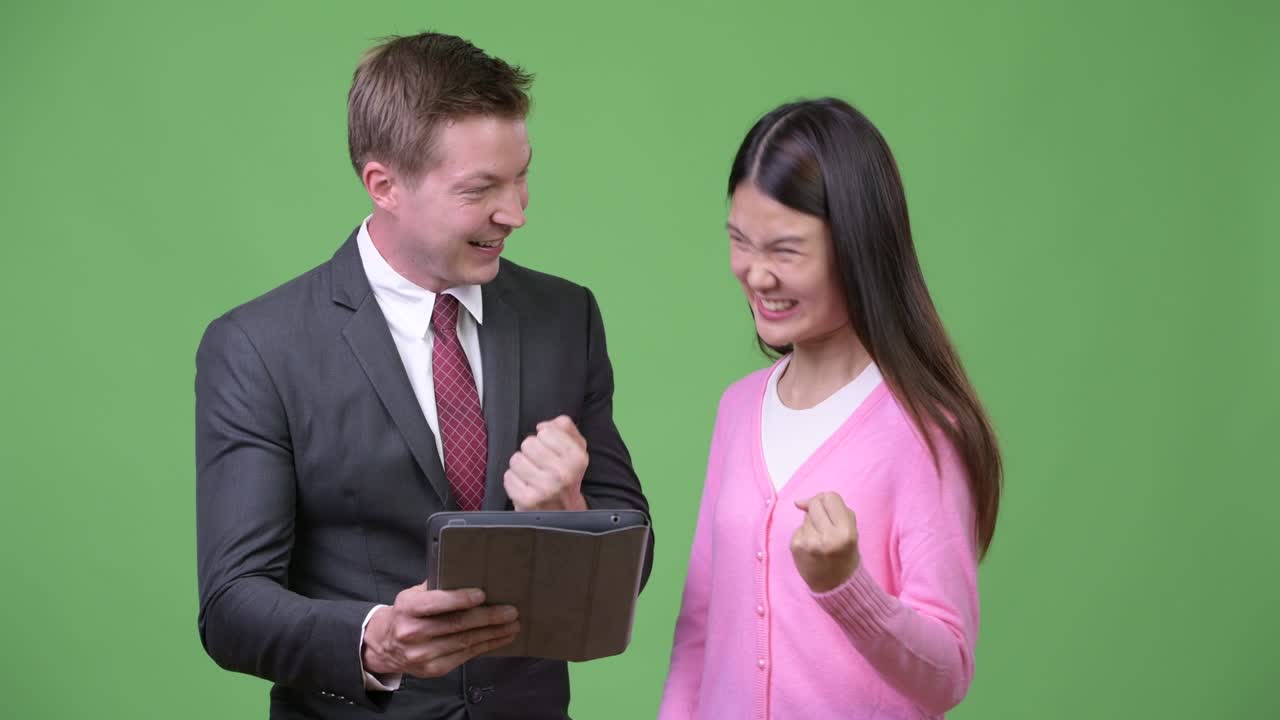 Young Asian woman and young businessman using digital tablet together