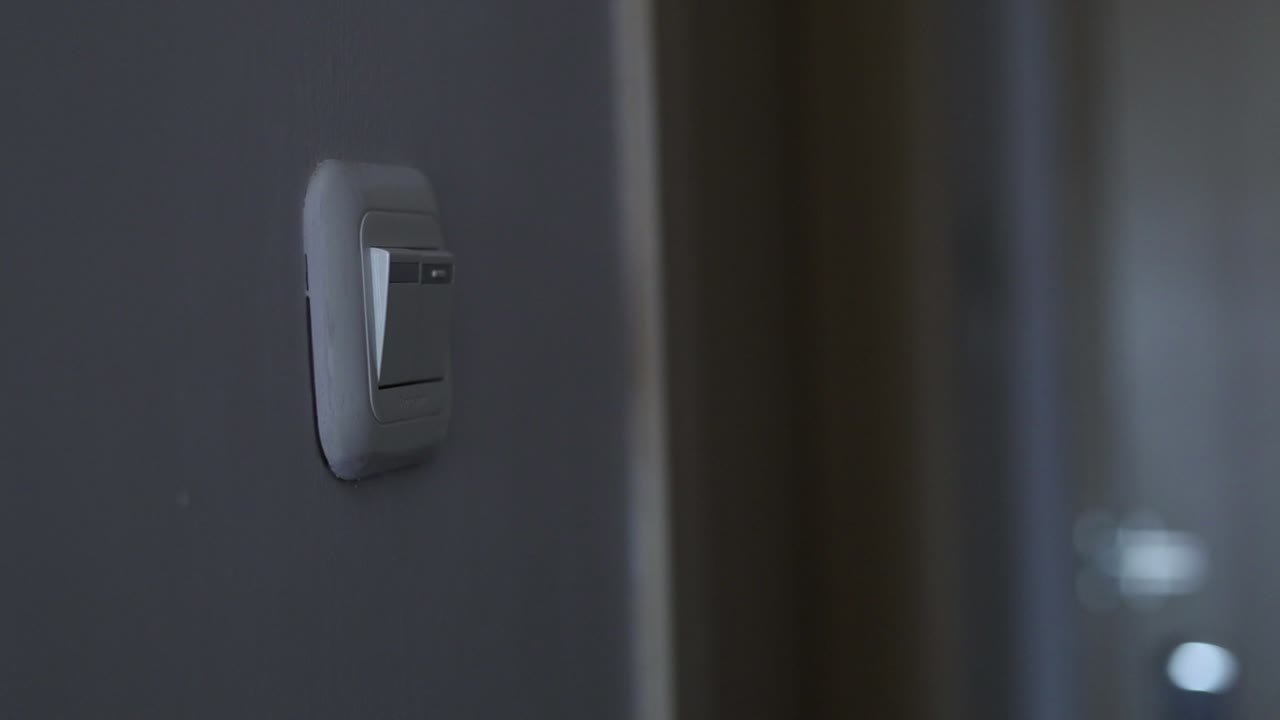 Close up shot of a man's hand turning light switch on in the room
