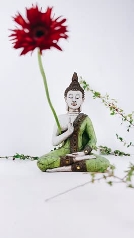 estatua de buda con una flor roja