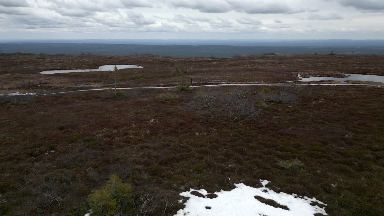 una mujer y su francés caminando por un camino de montaña con un pequeño lago detrás de ellos
