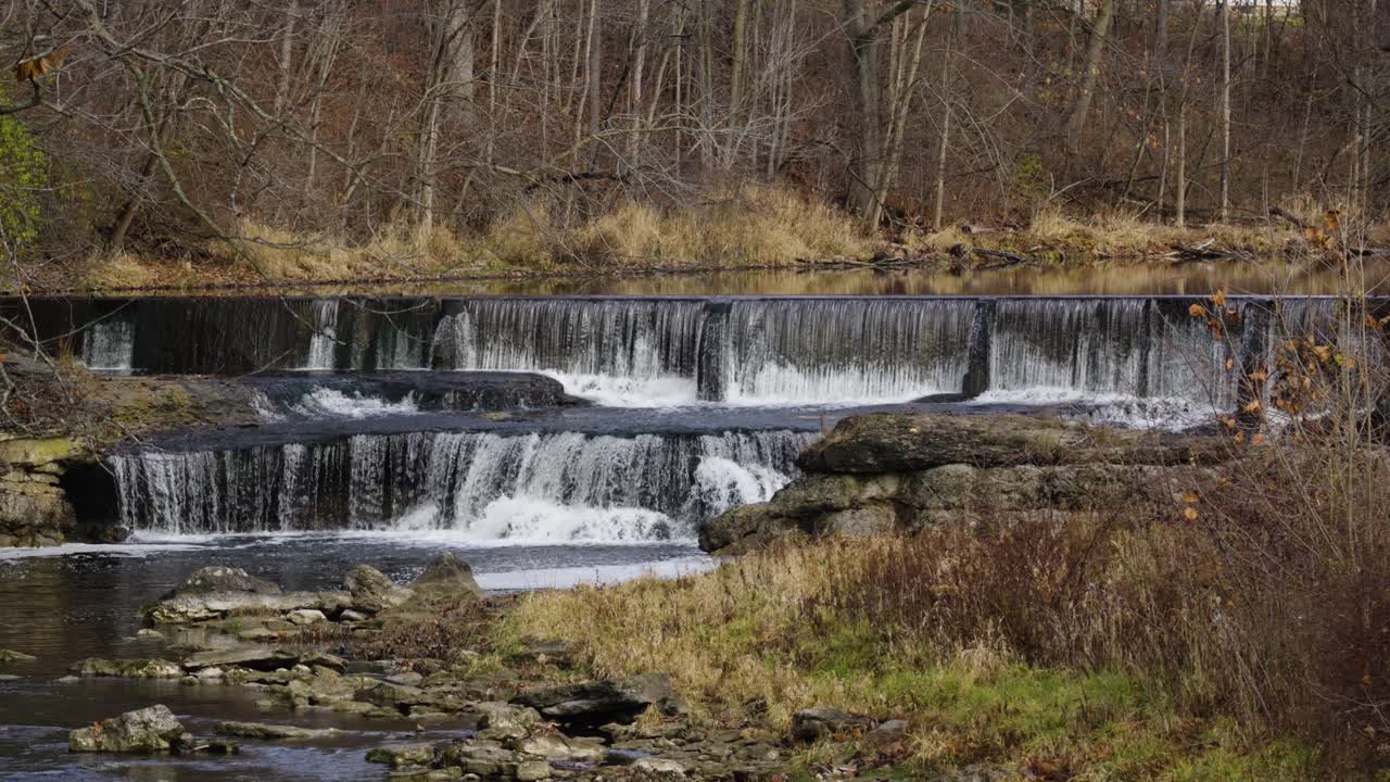 pequeña cascada de agua en cascada que se derrama por el pintoresco bosque de otoño