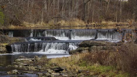 fresh small cascading waterfall spilling down scenic autumn woodland