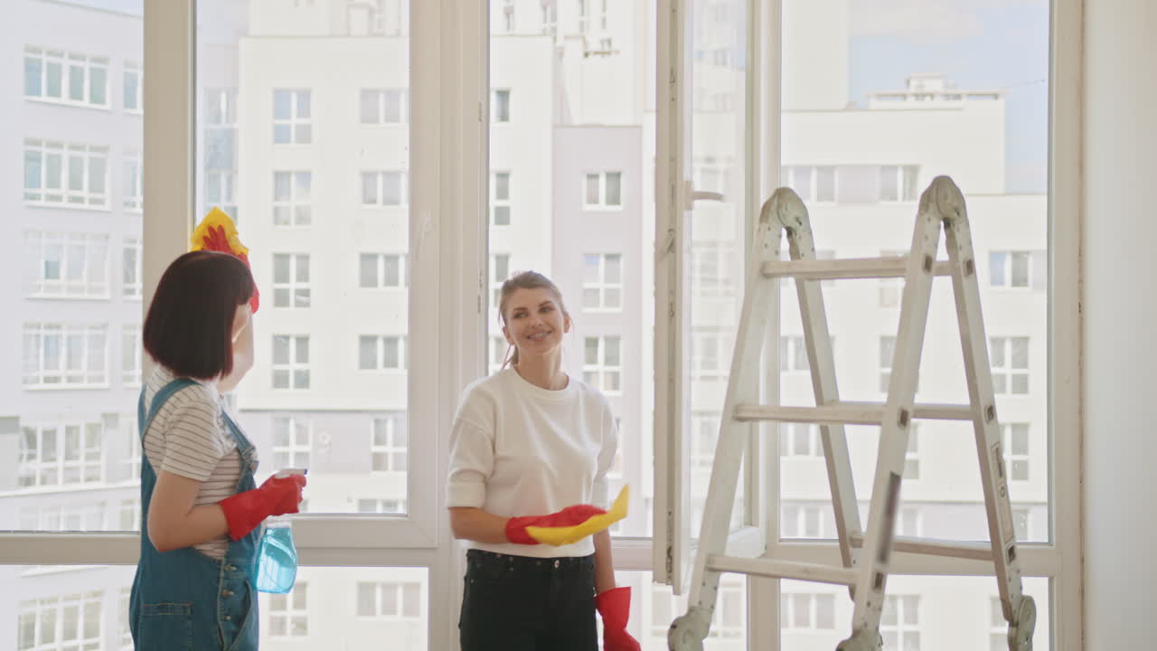 두 명의 여성이 함께 창문을 청소하고 있습니다.