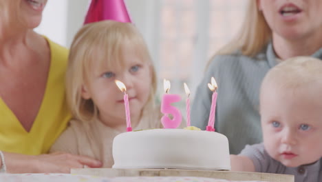 grandparents with mother at party singing happy birthday to granddaughter on fifth  birthday at home