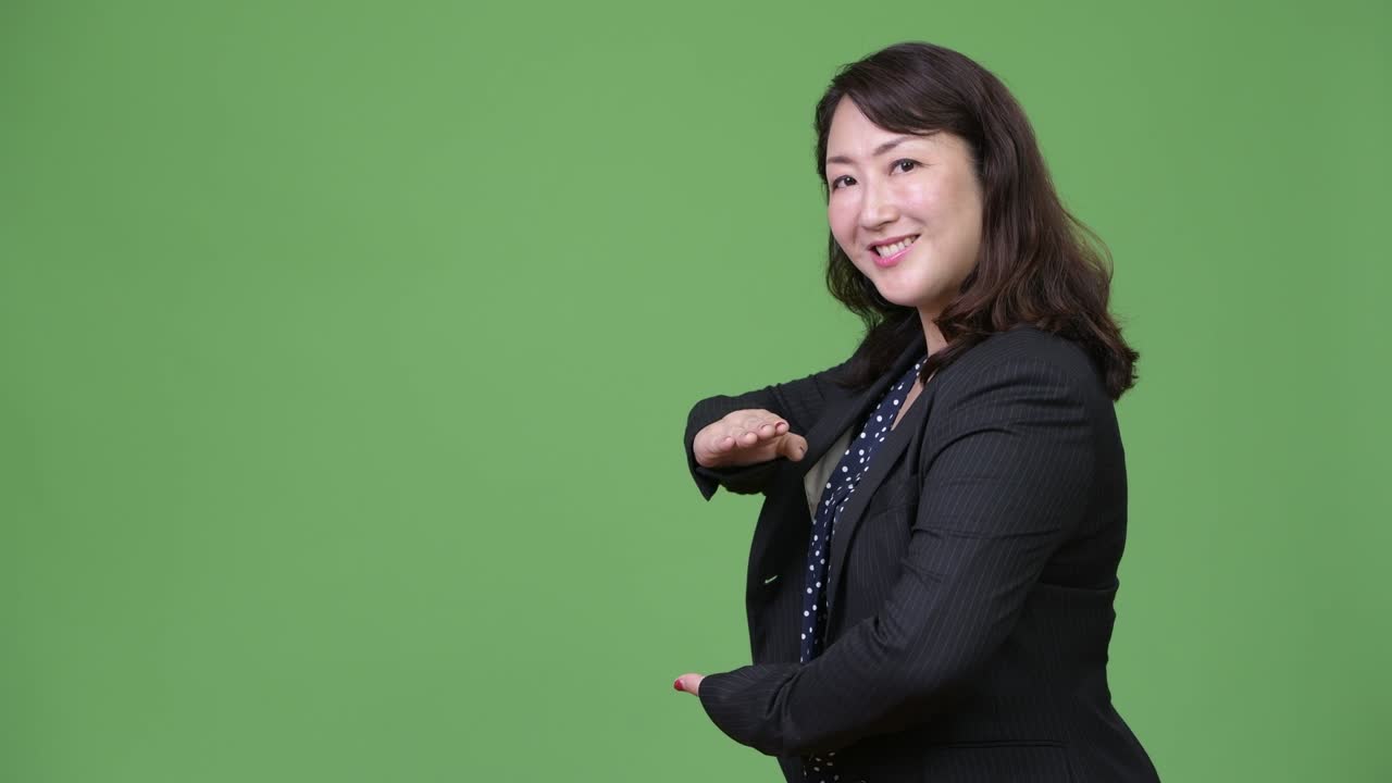 성숙하고 아름다운 아시아 사업가 여성이 무언가를 보여주고 있습니다.